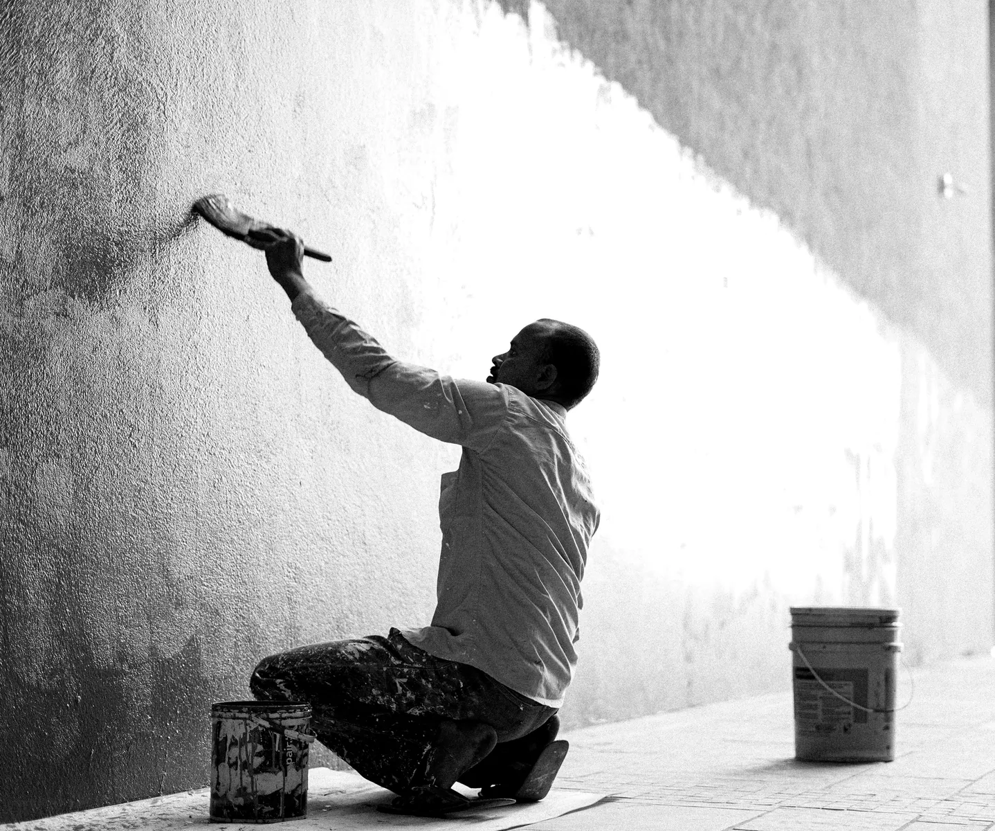 Painter coating a basement wall with a roller