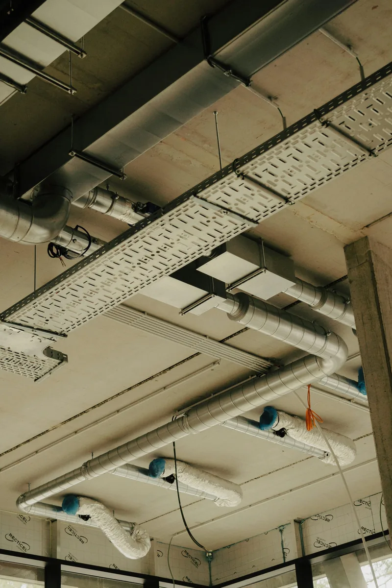 Open industrial ceiling with pipes, conduit, and lights