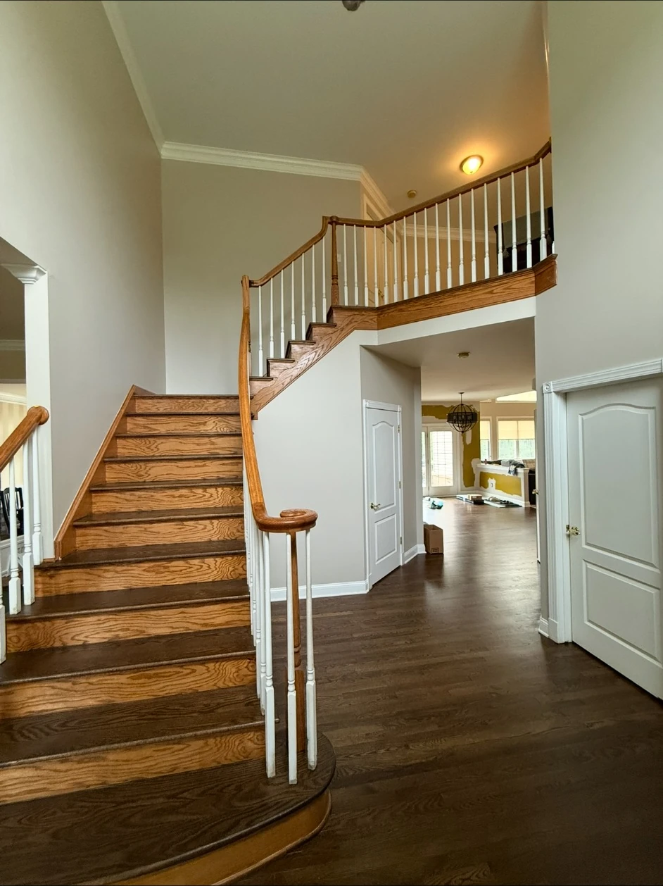 Completed two-story foyer with soft white-gray painted walls and wood staircase