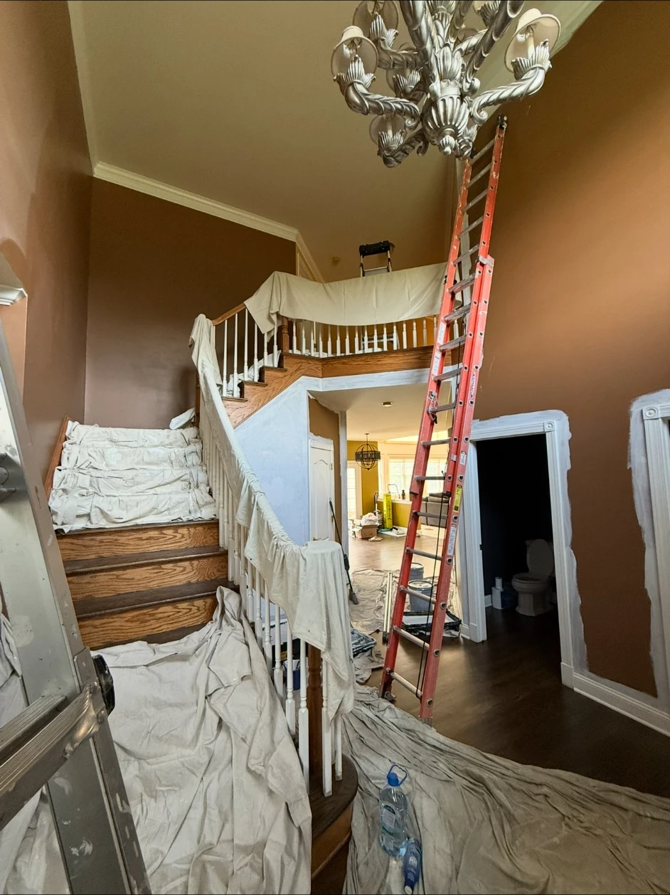 Two-story foyer protected with drop cloths and ladders before interior wall painting